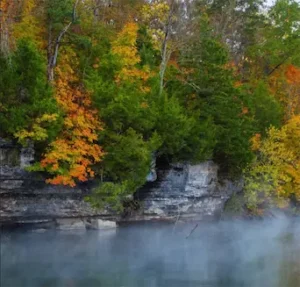 fog off a lake with trees in fall colors